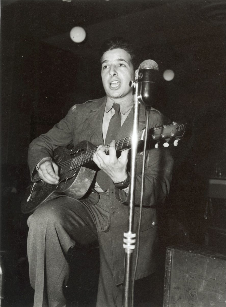 American soldier singing and playing guitar in performance with the U.S. Army Band in Brisbane (1942)