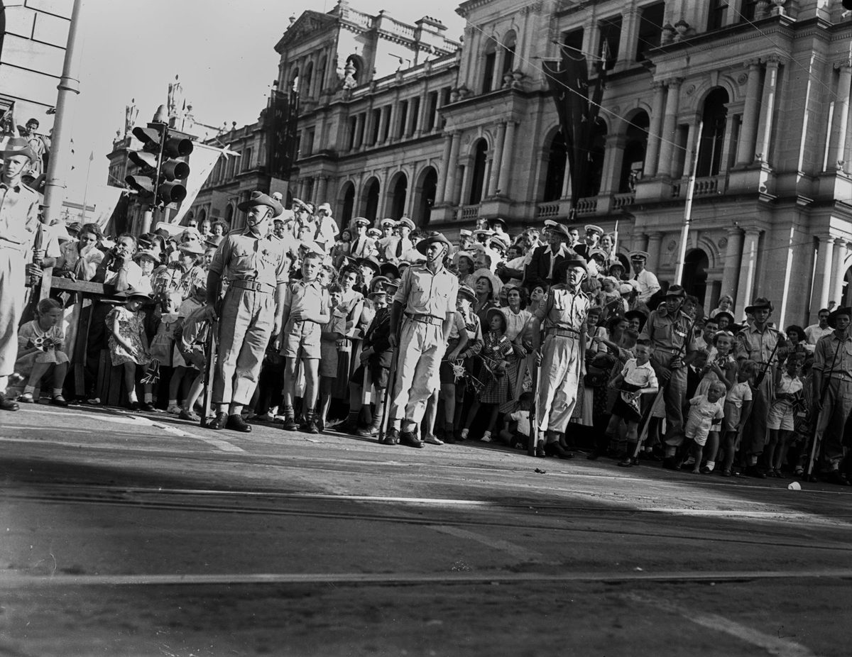 Small children peer out from between the soldiers while waiting for Queen Elizabeth II and Prince Philip to pass, March 1954, Brisbane