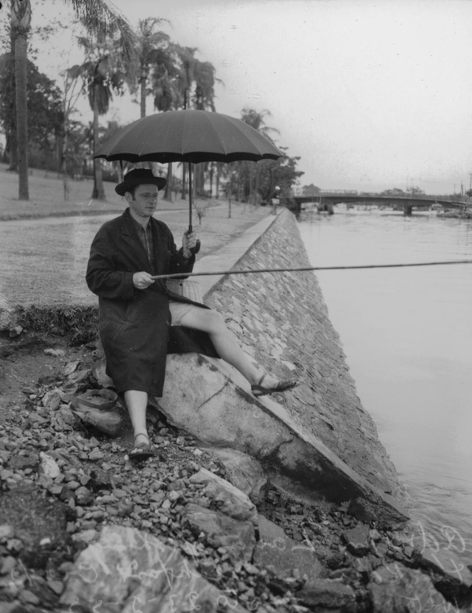 Adrian Zana fishing in the rain at Breakfast Creek, 1952