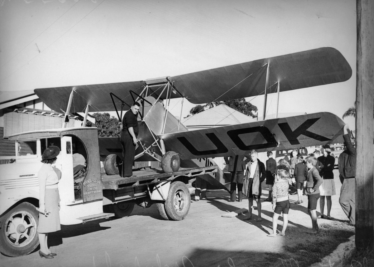 VH-UOK biplane being loaded onto a carrier's truck, 1939, Brisbane