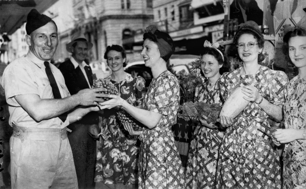 Liberty Week volunteers coaxing an airman into buying a pineapple, Queen Street Brisbane, November 1941, Brisbane City
