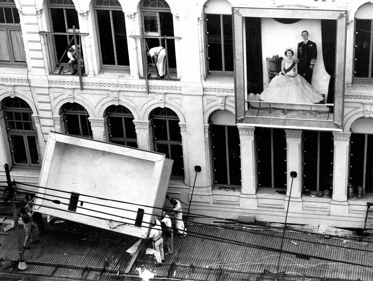 Workmen removing decorations from the Allan and Stark building after the Royal Tour in 1954, Brisbane