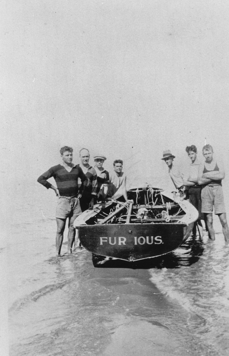 Crew standing next to the boat Furious on Bird Island during Easter, 1924