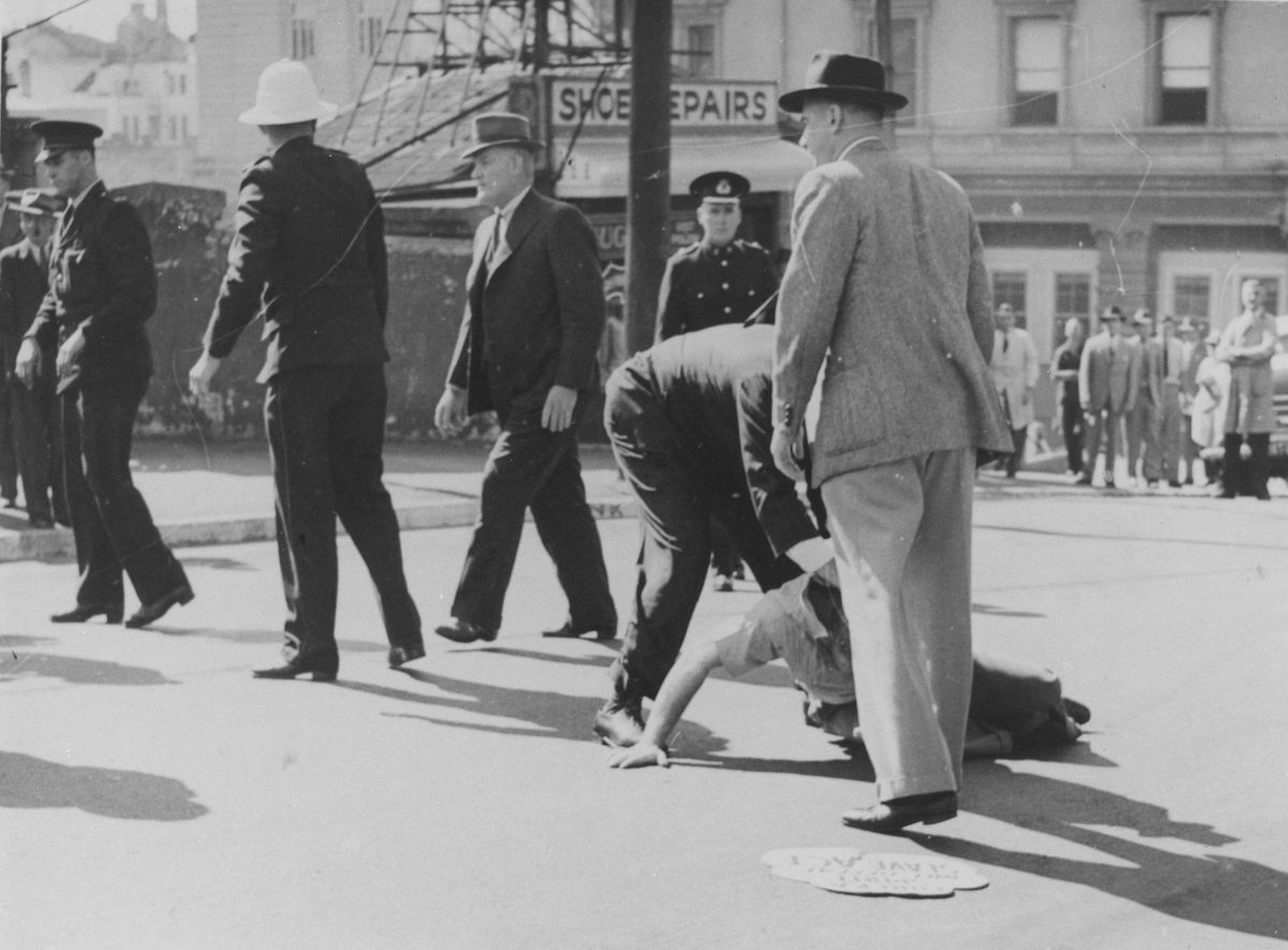 Injuired man lying on the ground during the Railway workers' strike, St Patrick's Day, Edward Street, Brisbane, Brisbane City (1948)
