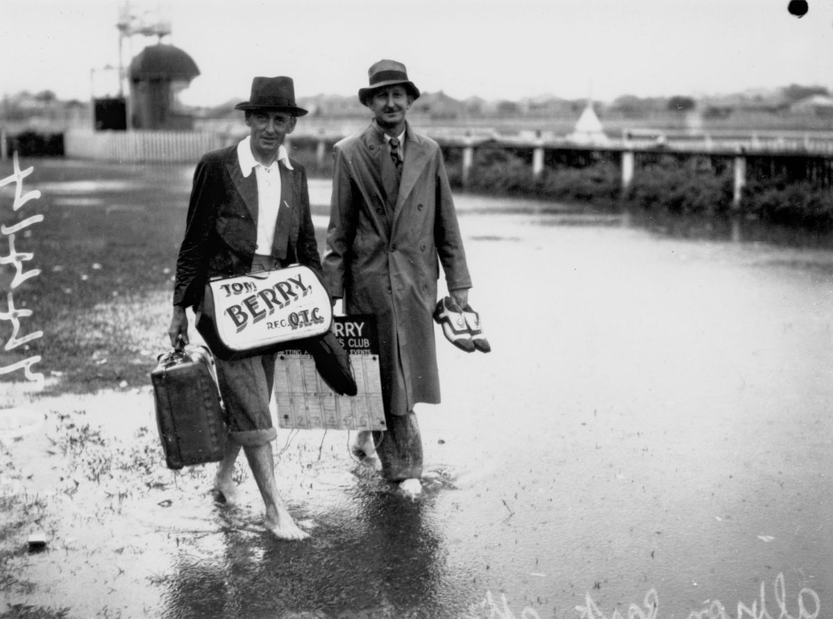 Barefoot bookmakers after a storm at Albion Park Racetrack, Brisbane, January 1941