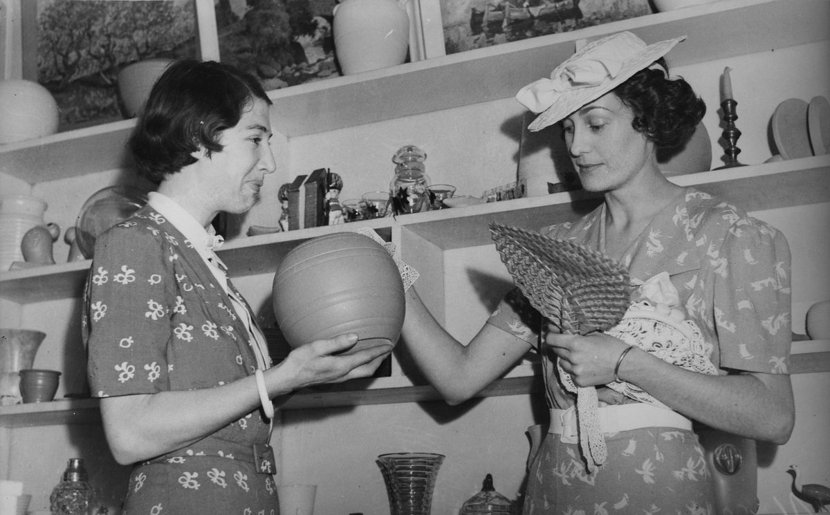 Miss Bess Hawkins admiring a pottery bowl in an art shop, 1940, Brisbane
