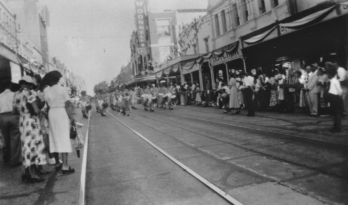 Military band marches down George Street as part of the procession for Queen Elizabeth II, Brisbane, 1954, Brisbane City