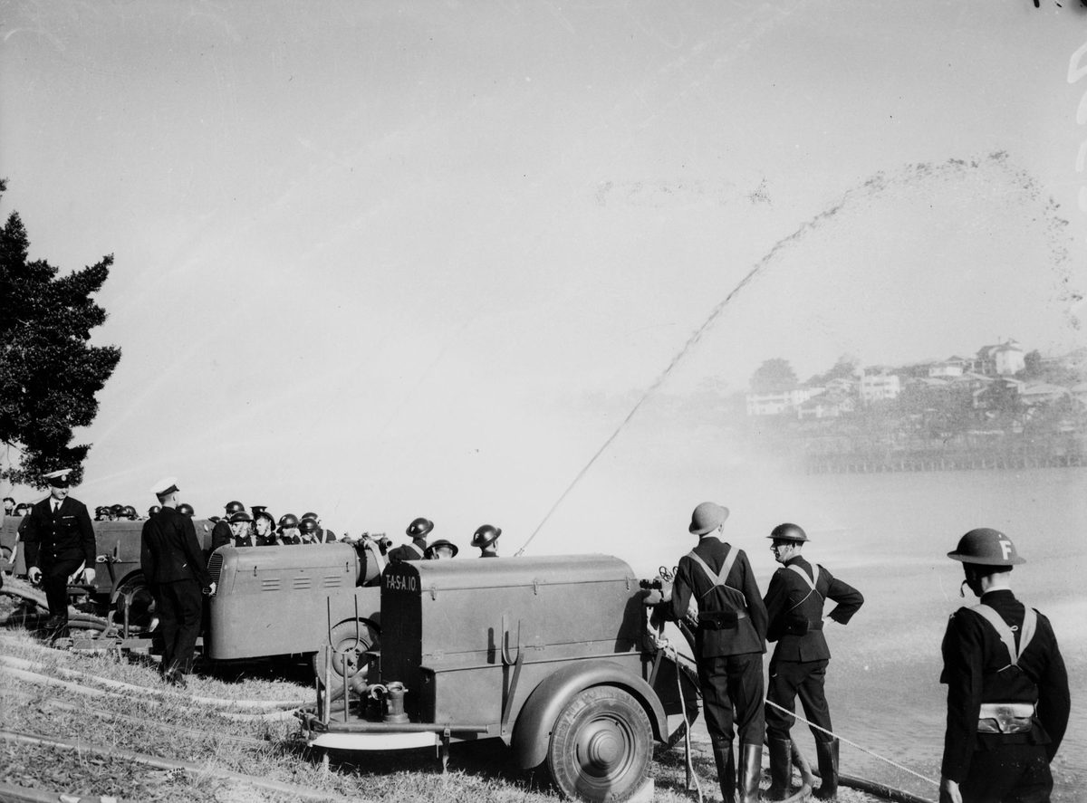 Volunteer firemen testing their hoses on the banks of the Brisbane River, August 1942