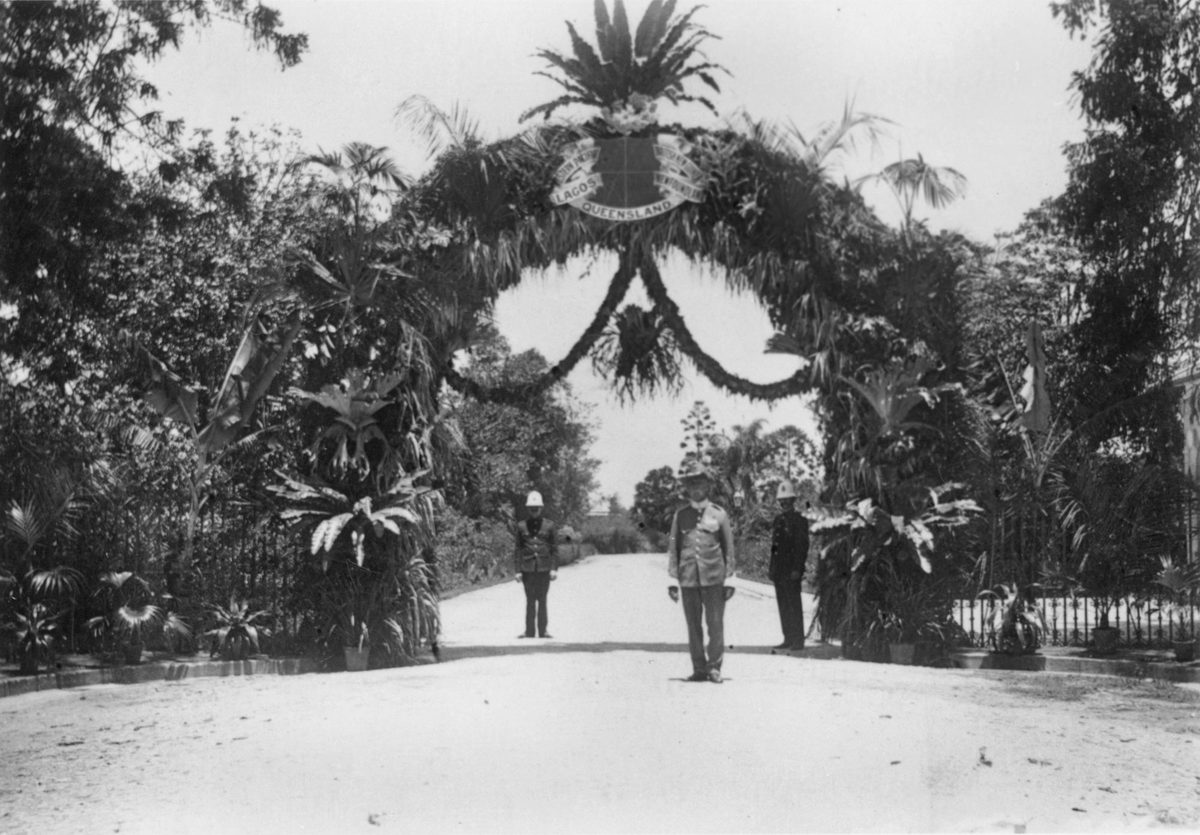 Arrival of the Govenor of Queensland, Sir William MacGregor, under the floral arch at the entrance to Government House, 1909