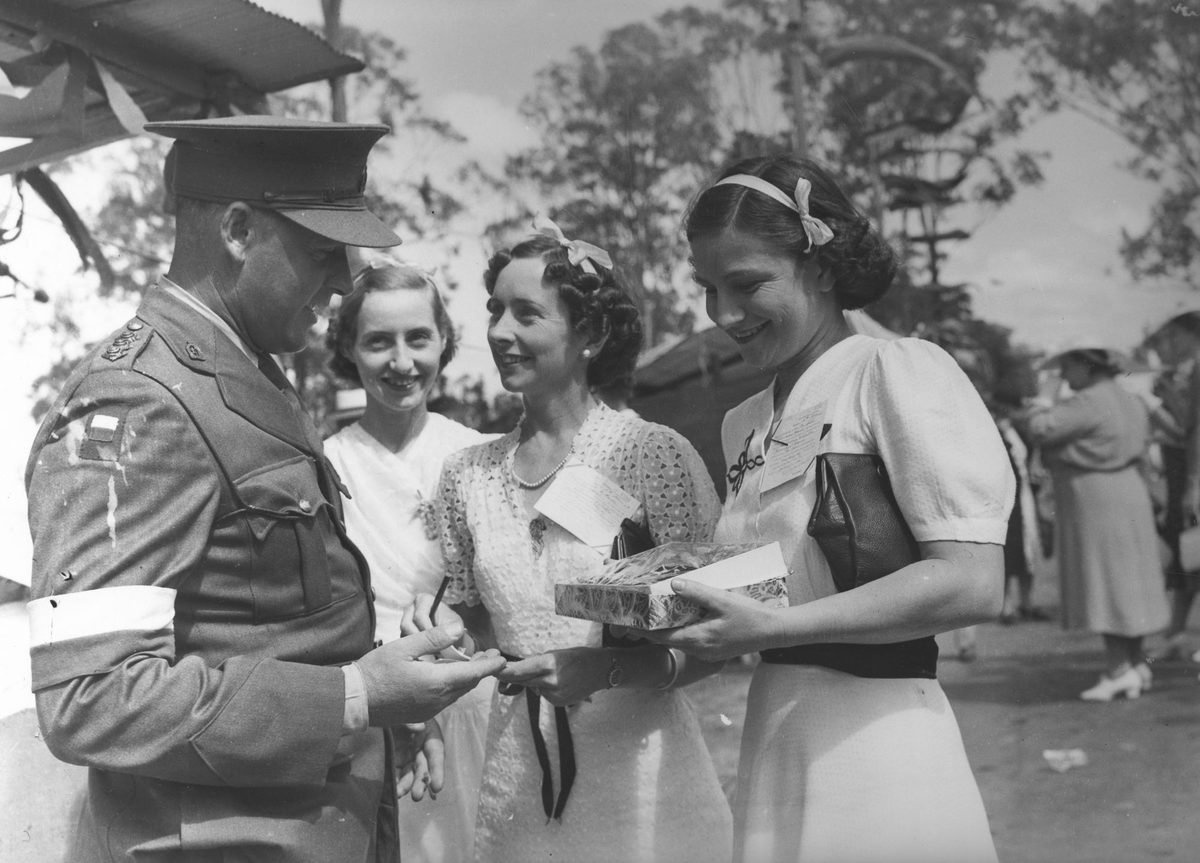 Three girls selling tickets to an officer at Red Cross Fete Government House, 1940, Bardon