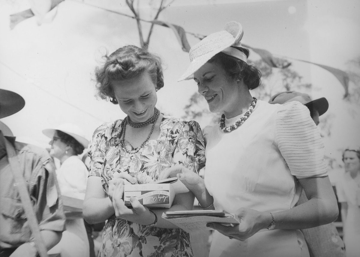 Two women smiling as they add ticket sales at Red Cross Fete Government House, 1940, Bardon