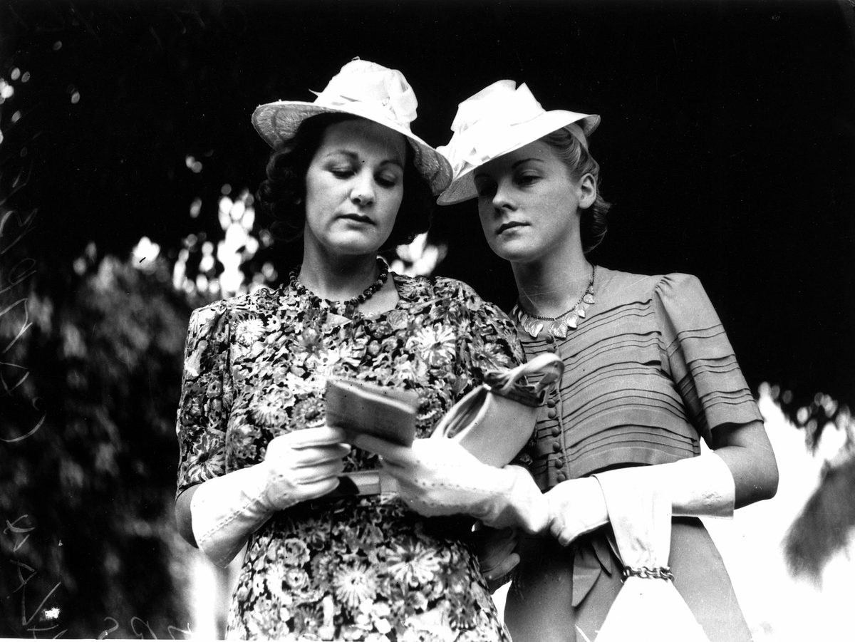 Miss Ethel Roche and Mrs Alan Campbell study the form guide at the races in Brisbane, 1940