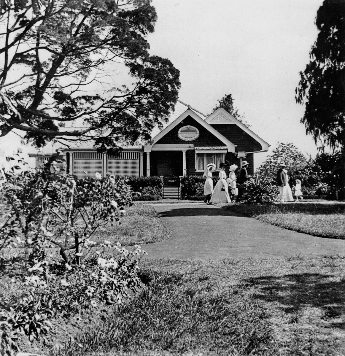 People strolling past the front of Mr Bailey's house in the Botanic Gardens, 1910